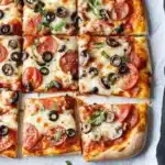 Sheet Pan Pizza: A Wonderful Comfort Crust You Will Love 29 Sliced sheet pan pizza with melted cheese and toppings on a baking tray